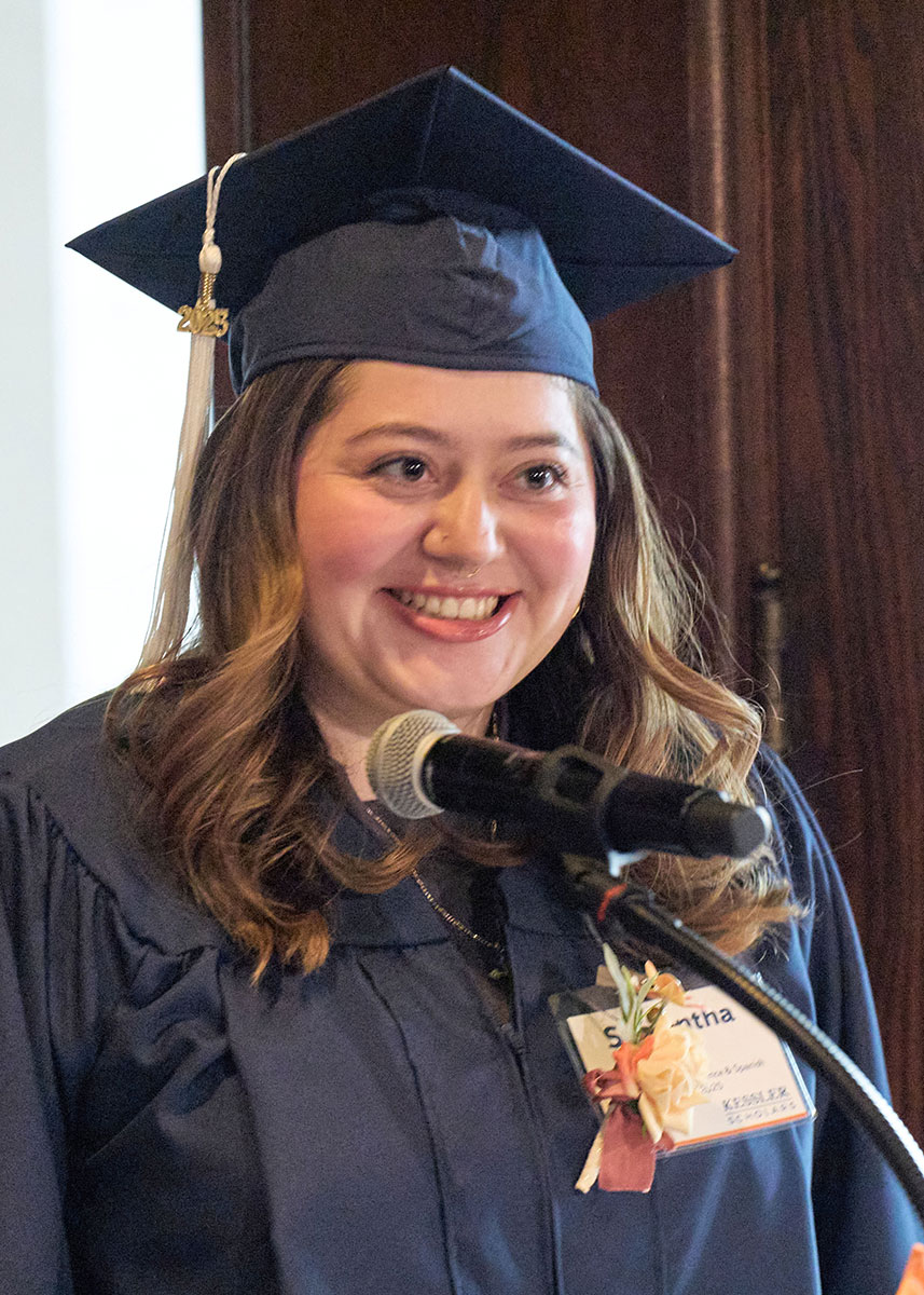 Graduate in cap and gown standing at podium